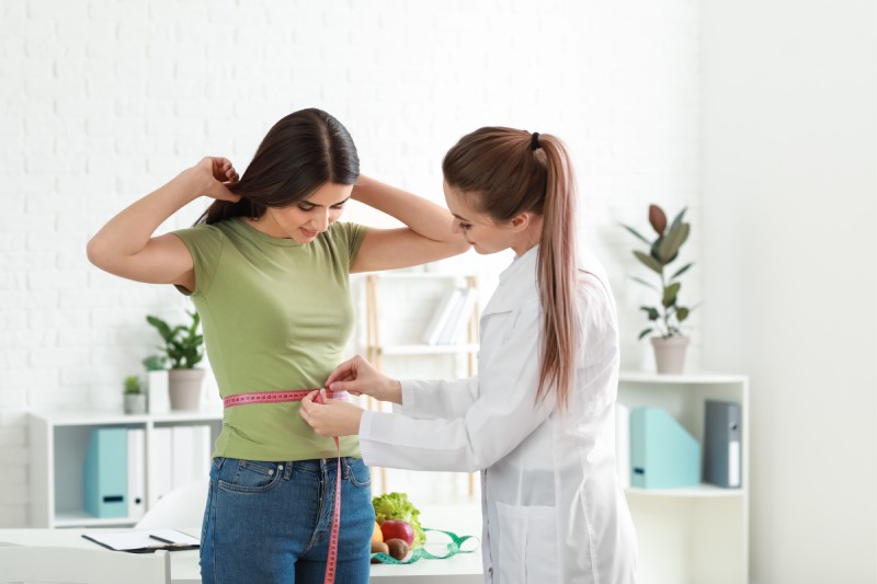 doctor measuring wait of women goiung through medical weight loss program and bhrt for weight gain
