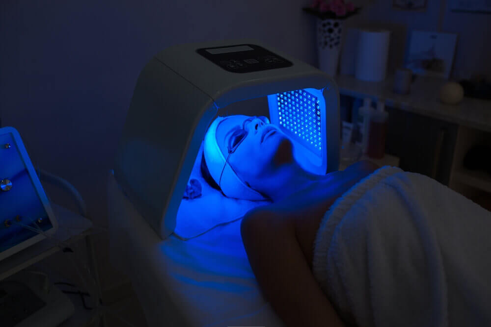 Patient wearing protective goggles during LED blue light skin therapy session.