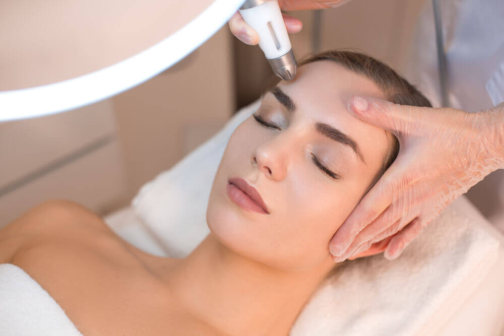 Close-up of microdermabrasion wand gently exfoliating facial skin to improve mild acne scars and texture.