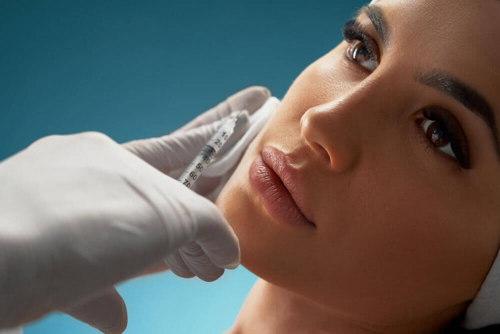 Cosmetic practitioner performing cheek filler injections on a patient in a clinical setting