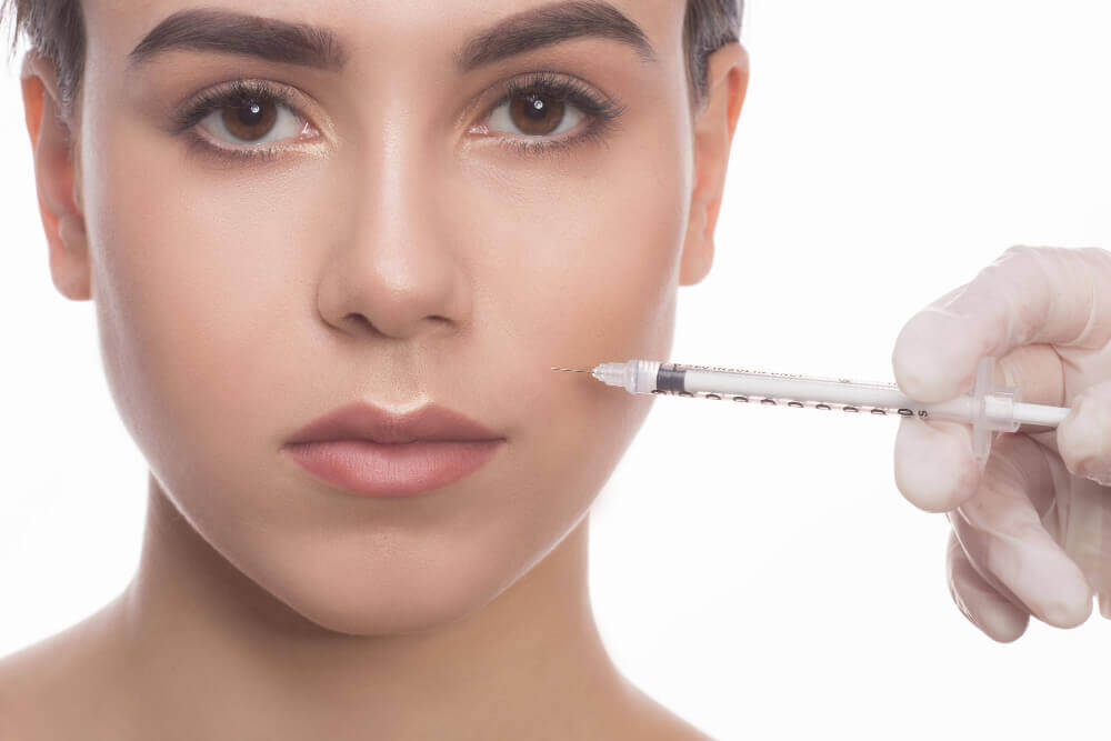 Licensed aesthetic practitioner administering Botox injections near smile lines in a professional Tampa medspa.